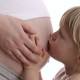 little girl kissing pregnant belly of her mum