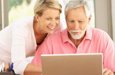 Adult Daughter And Senior Father Using Laptop At Home