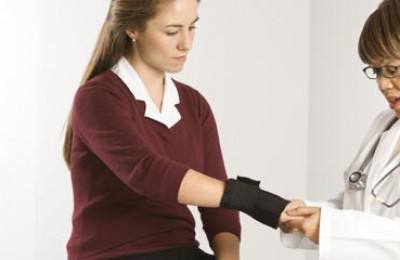 female doctor examining wrist of female patient