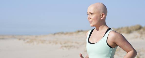 young woman with bald head jogging after chemotherapy